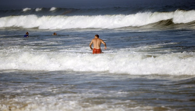 A man ventures into the water at Kinney Shores in Saco, where several people needed help after getting caught in a rip current Monday.