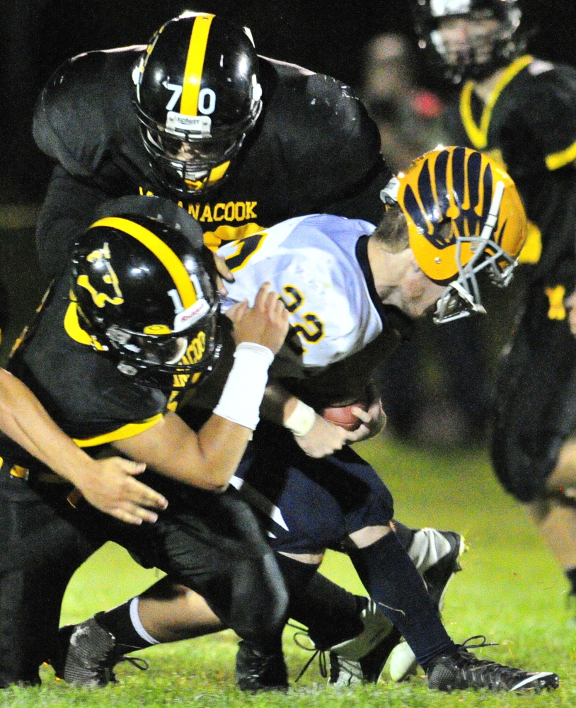 Maranacook’s Jordan Sansaricq, left, and Hunter Tims, top, wrap up Boothbay’s Xavier Downing during a Campbell Conference Class D game Friday night at Ricky Gibson Field of Dreams.