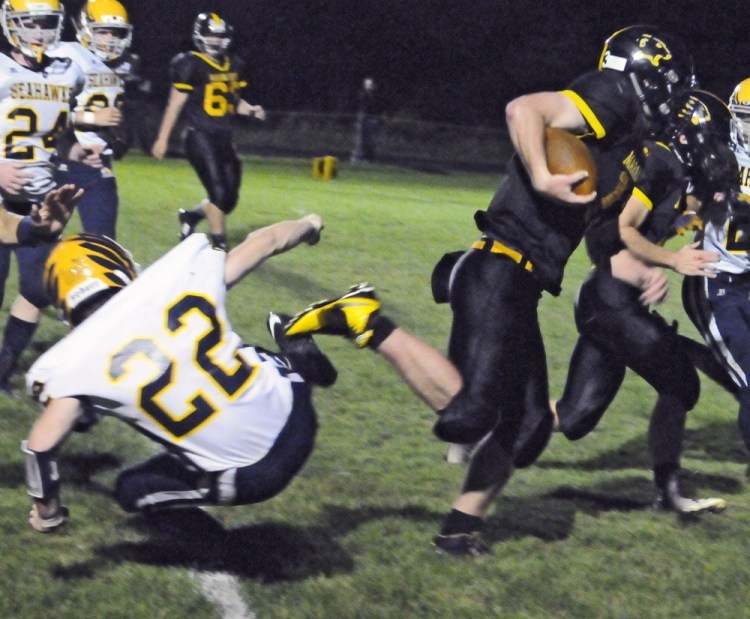 Maranacook quarterback Kyle Morand, right, runs past Boothbay’s Xavier Downing, left, en route to the end zone during the second quarter of a Campbell Conference Class D game Friday night at Ricky Gibson Field of Dreams in Readfield.