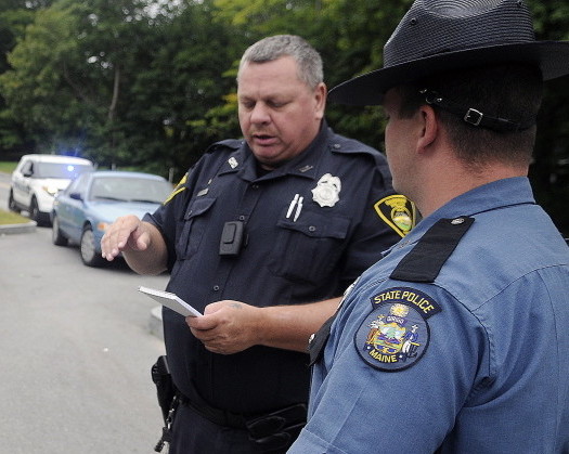 Gardiner Police Officer Eric Testerman, left, shares information with State Trooper Randy Hall Sunday on the Kennebec River Rail Trail in Farmingdale about a suspect involved in an assault on the trail. A man was transported to the hospital by ambulance following the assault that occurred before 10 a.m. across from Sheldon Street, police said.