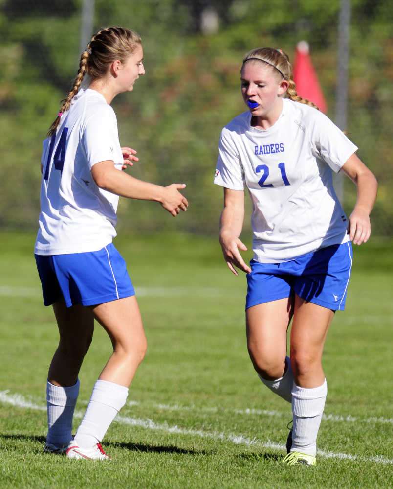 Oak Hill’s Charlotte Waterman (14), left, congratulates Oak Hill’s Brittany Marquis (21) after Marquis scored the Raiders’ first goal during a game Wednesday in Wales.