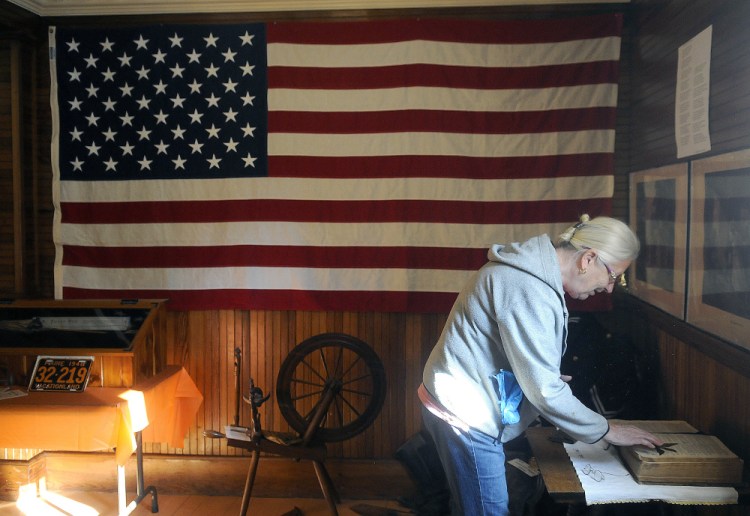 Linda Cobb unfolds a Bible at the Manchester Grange Thursday in preparation for a display by the Manchester Historical Society on Sunday.