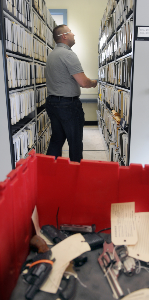 Staff photo by Andy Molloy
Augusta police Officer Brad Chase searches for records about firearms in storage Wednesday at the police station.