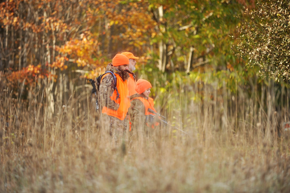 Ronald Garcia, foreground walks out of the woods with his daughter Jadee, 11, and her uncle Cary Kelly, back, in Harmony last Saturday, which was Youth Deer Day. Firearms hunting season opens for Maine residents Saturday and for non-residents Monday.