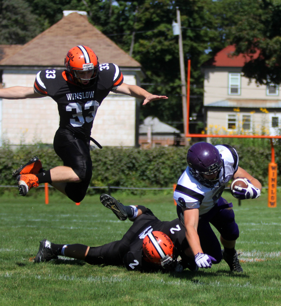 Winslow’s Ryan Fredette (33) assists Patrick Hopkins (2) in bringing down John Bapst’s Spencer Baron during first-half action of a regular season game.