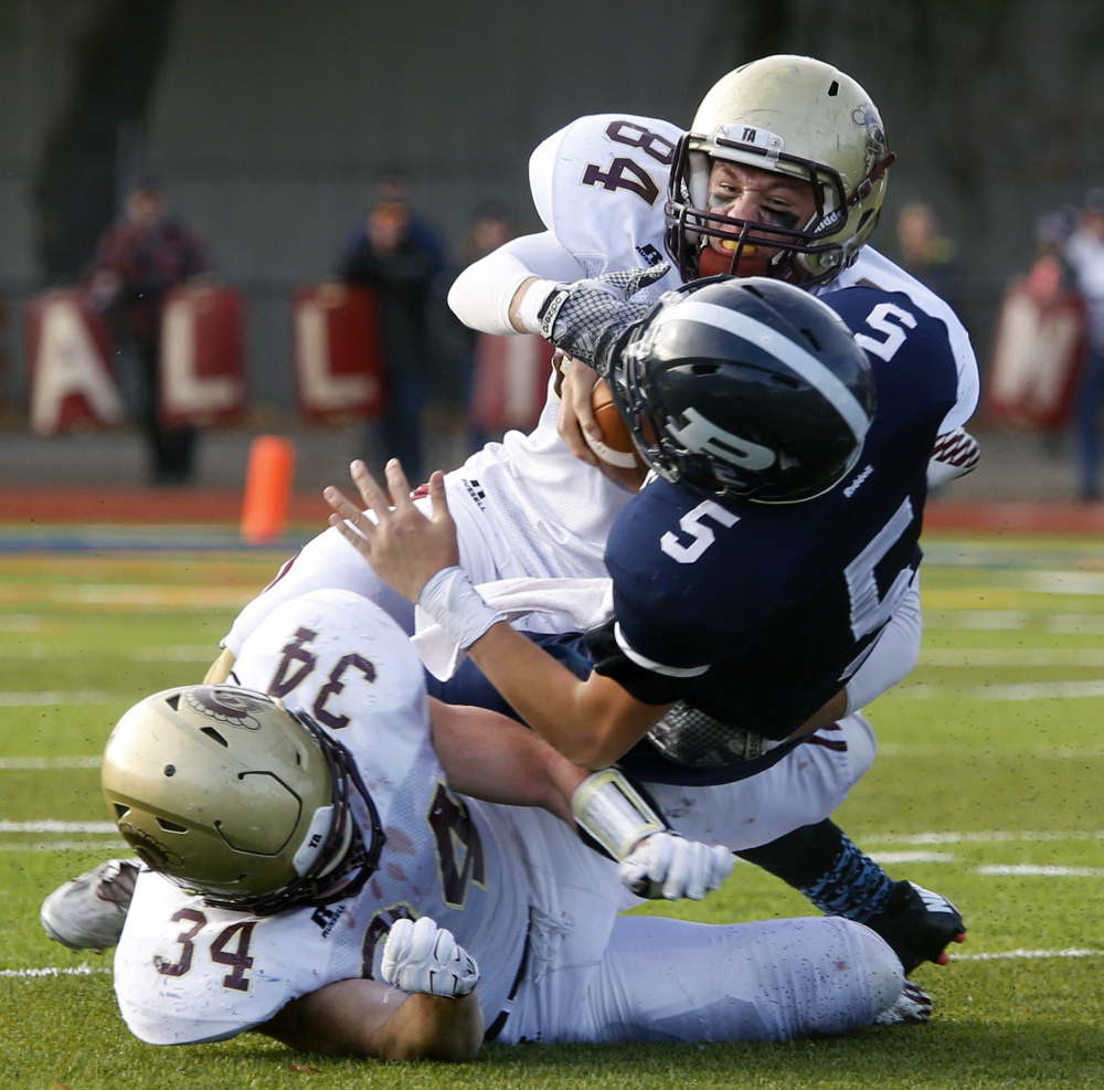 Portland quarterback Issiah Bachelder is unable to avoid a Thornton Academy defensive surge that includes Evan Russell, top, and Owen Elliott.