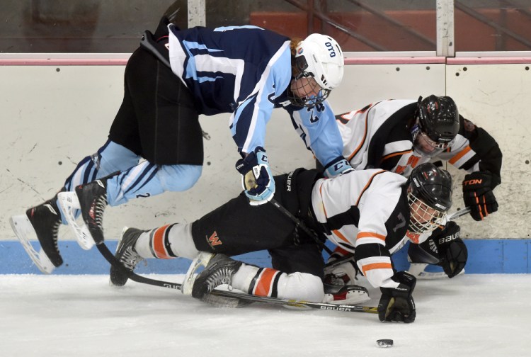 Winslow forward Jimmy Fowler, bottom center, gets knocked over by Old Town/Orono’s Chris Hoxie during a Class B North game Saturday night at Sukee Arena.