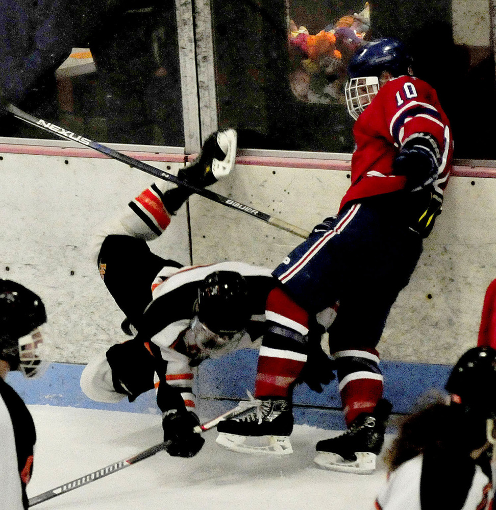 Winslow’s Nick Gurney hits the ice after colliding with Messalonskee forward Brandon Nale during a Class B North game Wednesday at Sukee Arena.