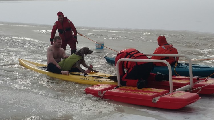 Fryeburg firefighters accompany Chappy the Weimaraner back to shore after rescuing him from Lovewell Pond on Thursday.