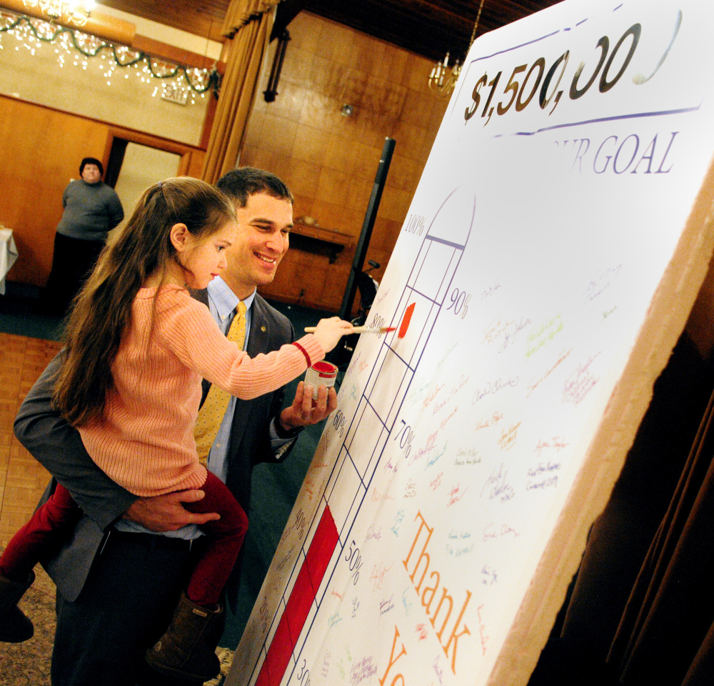 Craig Garofalo lifts up his daughter Lydia to mark the level of fundraising progress in the United Way of Kennebec Valley campaign thermometer on Tuesday at the Governor Hill Mansion in Augusta. Executive director Rob Gordon said the United Way expects to have raised $1,535,784 during the annual campaign.