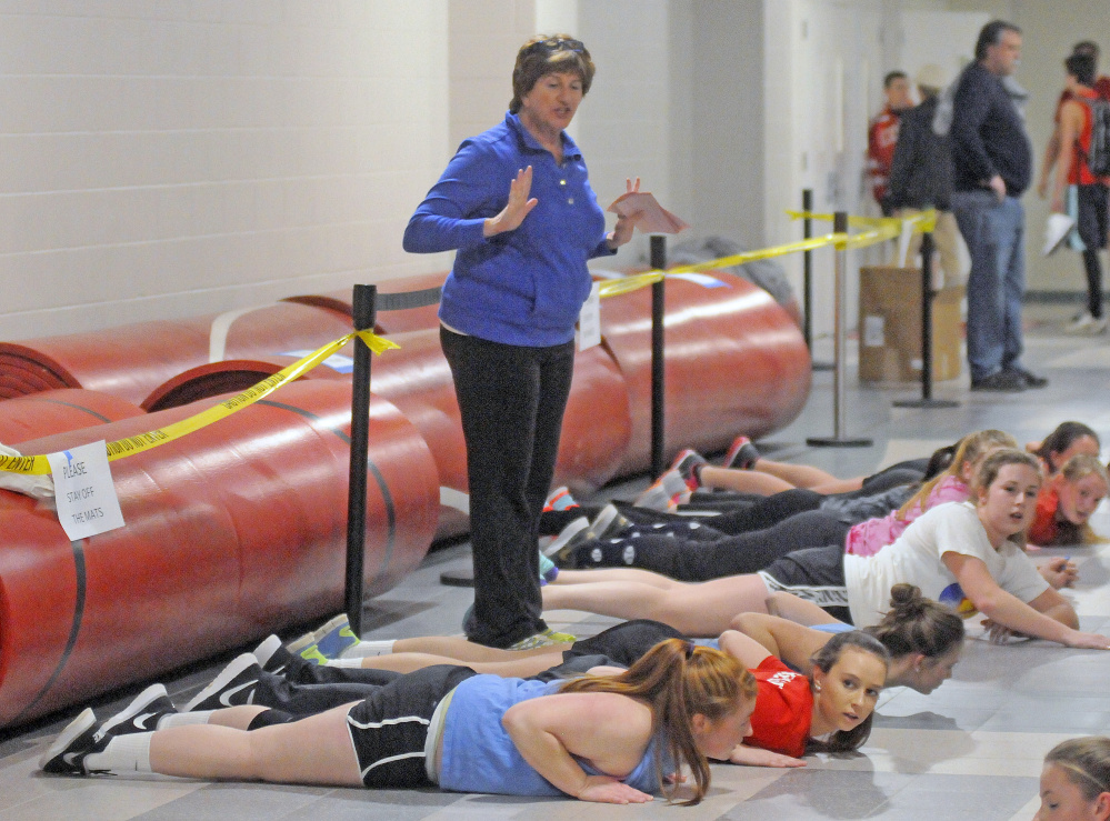 Cony High School softball manager Barbara Gaslin oversees stretching during the first day practice Monday at the Augusta school.