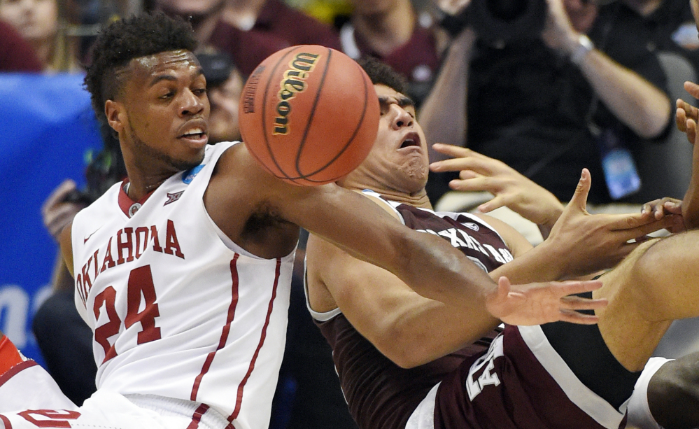 Oklahoma guard Buddy Hield, left, and Texas A&M center Tyler Davis battle for a loose ball in the second half of Oklahoma’s win Thursday night in Anaheim, Calif.