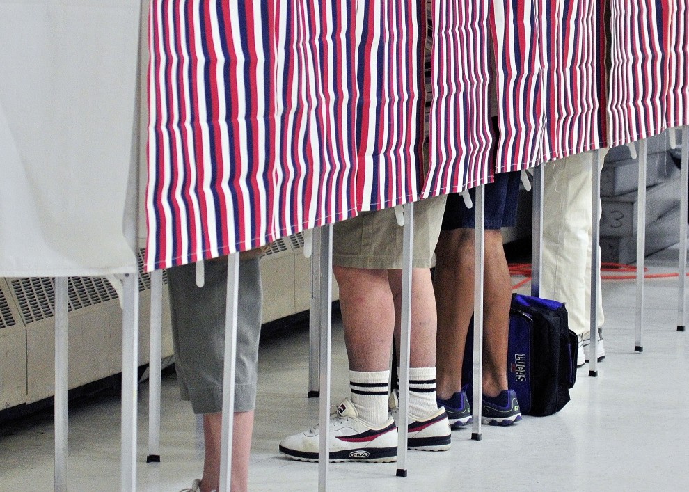 Four voters cast ballots June 10, 2014, in voting booths in the Augusta State Armory. The town of Monmouth is trying to decide whether to appoint town employees as election clerks.