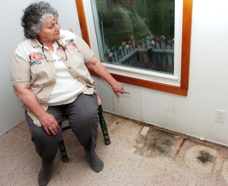 Jan Martin points to where water has seeped inside from a window and contributed to black mold on the carpet in a room of her home in Skowhegan on Sunday. Martin is having trouble getting the help she needs to solve the problem.