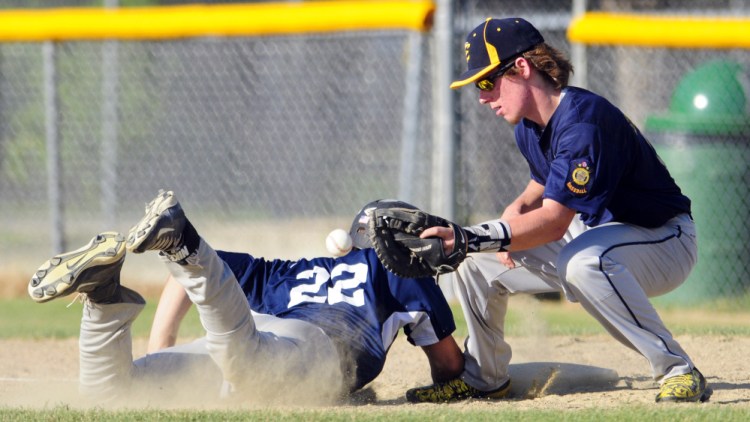 Gardiner runner Matt Clifford dives safely back to first as the pick-off attempt gets away from Augusta first baseman Mark Buzzell during a Zone 2 American Legion game Tuesday night in Augusta.