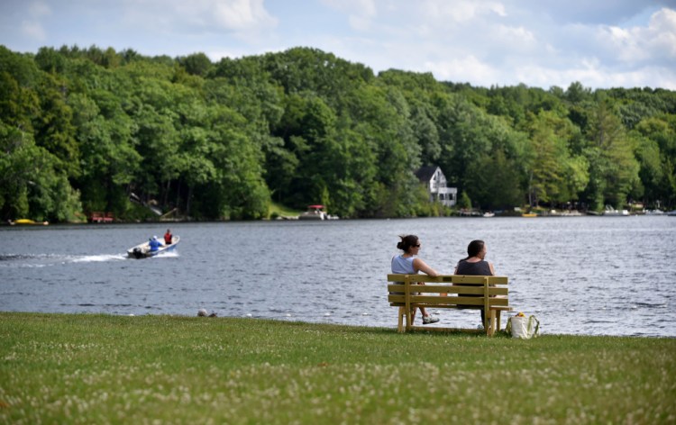 Beachgoers take in the sunshine Thursday at a public bench at the Oakland town beach on Messalonskee Lake. The town's Gazebo Committee is moving forward with an effort to erect a gazebo there.