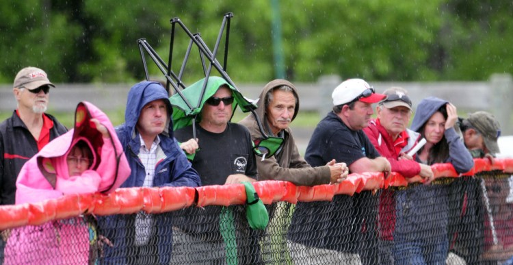 Fans take cover along the third base line at Cony Family Field in Augusta as rain began to fall during the Class C/D senior all star game Thursday at Cony Family Field in Augusta.