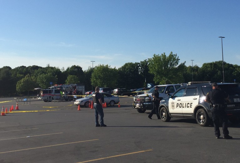 Crime scene tape surrounds a Volkswagen Jetta on Sunday evening in a parking lot at the Wal-Mart store in Augusta as police officers look for evidence after a report of shooting at the site.