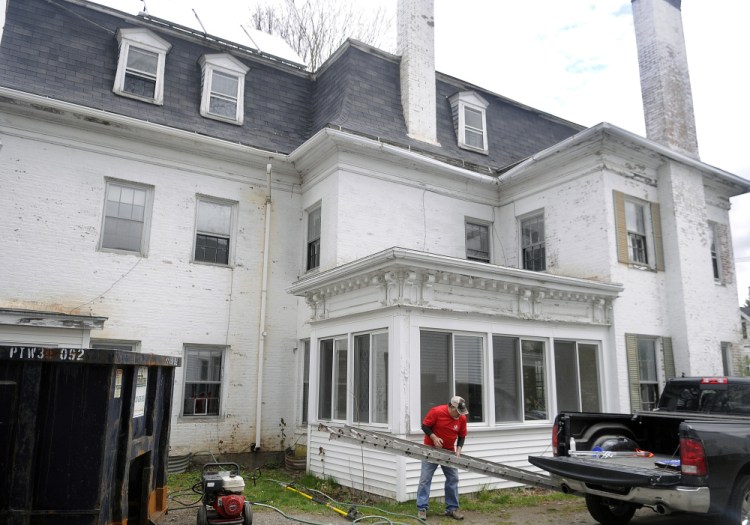 Volunteer Norm Ginish unloads a ladder at the Betsy Ross House of Hope on May 4 at 8 Summer St. in Augusta, where work has been halted until a city board can review the application.