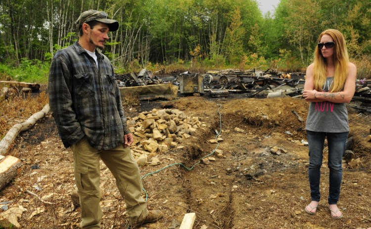 Fire victims Eric and Kristie Baker stand on their property in Gardiner last week after a fire destroyed their home. Police arrested Joseph Manganella, 35, of Gardiner on Friday on a charge of arson related to the case.