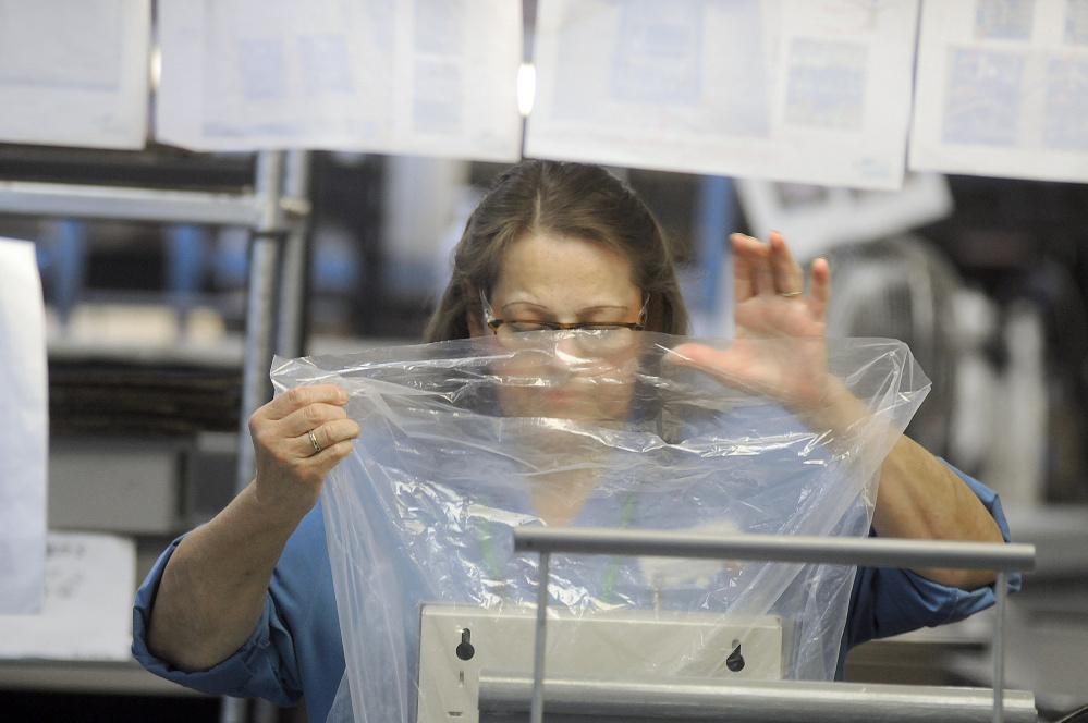 Tricia York packages a product after testing it at Alternative Manufacturing Inc. in Winthrop Wednesday.