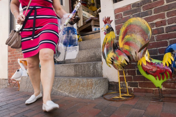 A shopper leaves the Maxwell Pottery Outlet in Portland's Old Port, a popular destination for visitors. Some tourism officials received emails over the weekend from travelers who were canceling trips or saying they won't return.