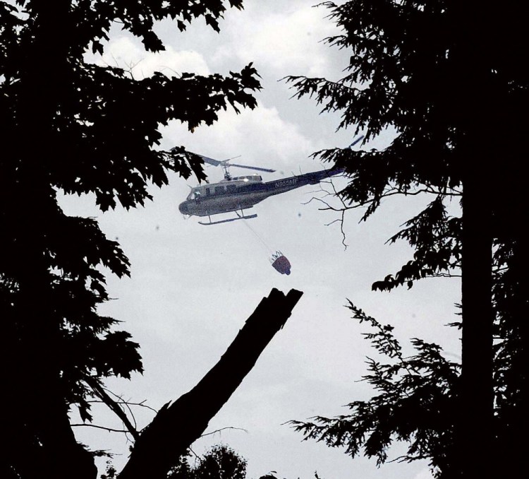 A Maine Forest Service helicopter dumps water over a woods fire Tuesday off the Gray Road in Vassalboro. The fire left a few hot spots that flared up again Thursday.