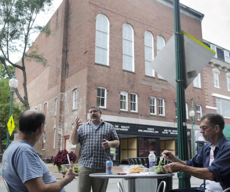 Johnson Hall Performing Arts Center Executive Artistic Director Mike Miclon speaks on Thursday to Greg, left, and Danny Chapman in front of the theater on Water Street in Gardiner, which will soon begin to benefit from financial support from Kennebec Savings Bank.