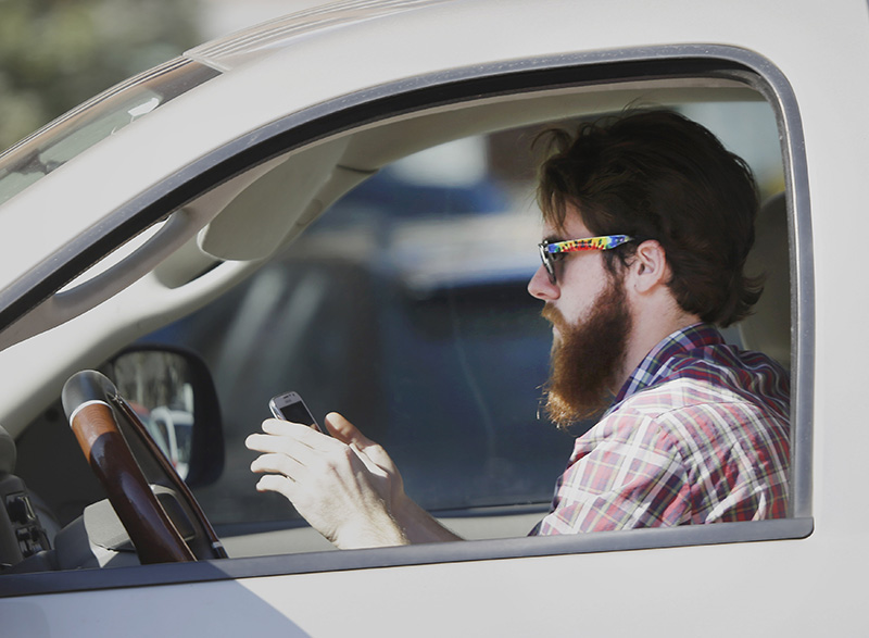 FILE - In this Feb. 26, 2013 file photo, a man uses his cell phone as he drives through traffic in Dallas. In a new survey, 98 percent of motorists who own cellphones and text regularly were aware of the dangers, yet three-quarters of them admit to texting while driving, despite laws against it in some states. Two-thirds said they have read text messages while stopped at a red light or stop sign, while more than a quarter said they have sent texts while driving. (AP Photo/LM Otero)