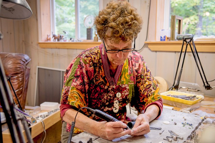 Valerie Hoff uses an electric drill to shape moose bone into fine jewelry Saturday in her Mont Vernon studio.