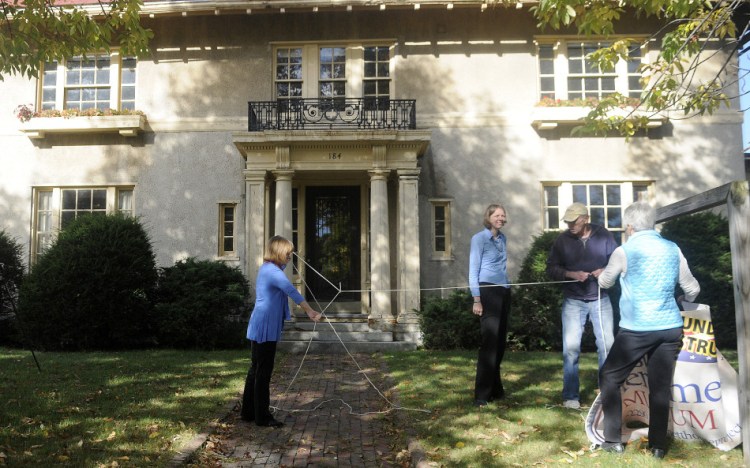 Genie Gannett, left, unknots a rope that Rebecca Lazure, second from left, Denis Thoet and Susan Gross used to hang a sign Monday for the First Amendment Museum in front of the Gannett House in Augusta. Gannett serves as chairman and president of the board, Lazure serves as executive director, and Gross and Thoet are on the board.