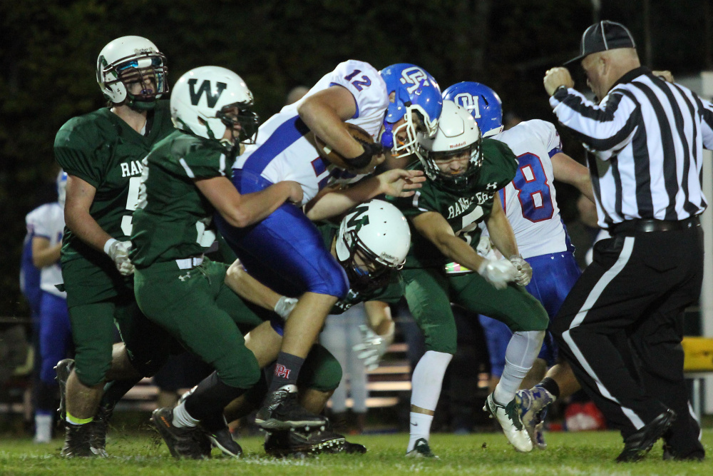 Oak Hill High School quarterback Matthew Strout gets brought down by Winthrop/Monmouth's Antonio Meucci, left, and a host of Rambler defenders during first-half action last Friday night in Winthrop.