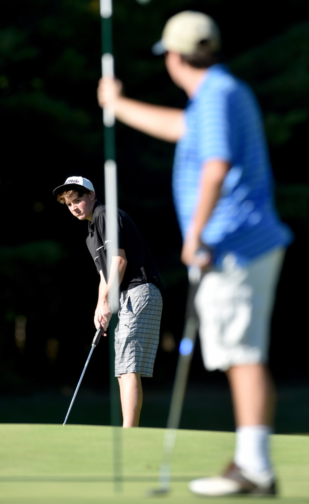 Erskine senior Robert Harmon putts as teammate Brandon Keezer, right, holds the flag during practice at Natanis Golf Course in Vassalboro on Wednesday.