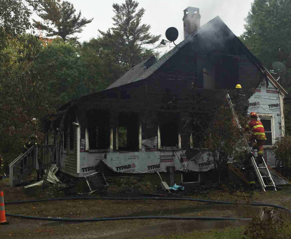 Firefighters try to put out a fire at 116 Pleasant Cove Road in Boothbay on Sunday morning. Two people died and four others injured.