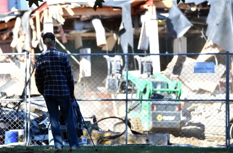 Raymond LaPointe watches and records on video the demolition of the former Levine's building in downtown Waterville on Thursday.