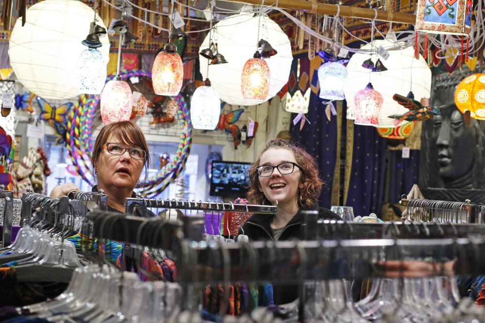 Rae Jett, right, a year-round worker at Mexicali Blues, helps a customer pick out a tea light Friday. To try to attract seasonal workers, the retailer has raised the hourly pay to $11.