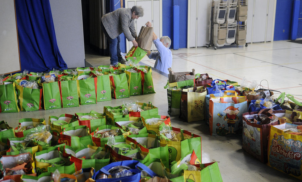 Judge Rae Ann French and her husband, Fern LaRochelle, deposit groceries into recycled bags donated by Hannaford during the Monday give-away of Thanksgiving groceries at St. Michael School in Augusta.