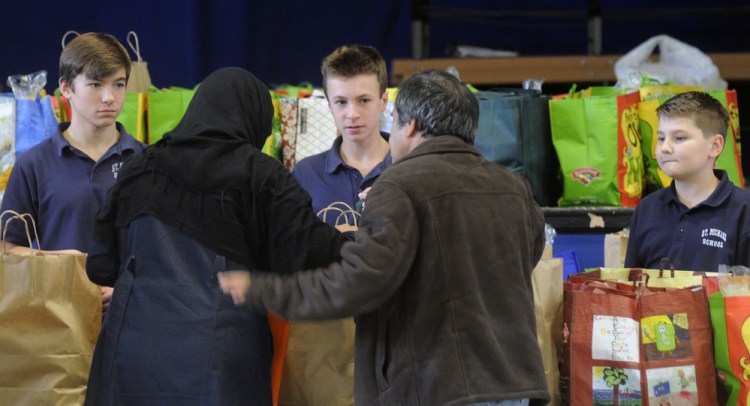 St. Michael eighth-graders help people collect bags of groceries Monday for the Thanksgiving holiday at the private Catholic school in Augusta. Several people collected the donated meals assembled by the students.