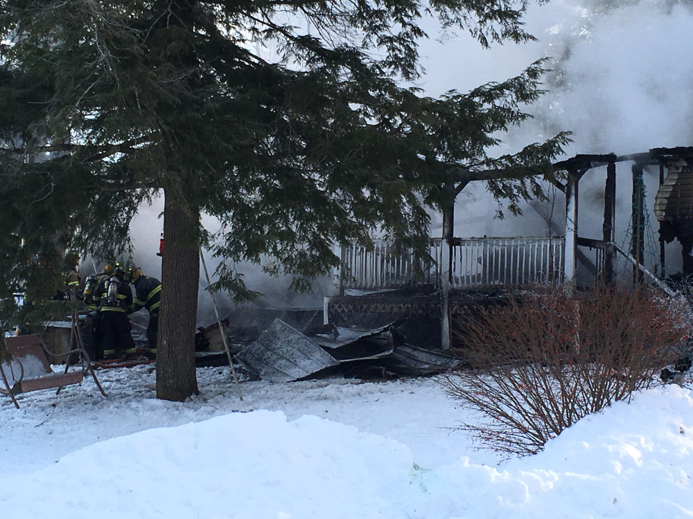Firefighters continue to work in frigid weather Tuesday morning to put out a mobile home fire on Blue Rock Road in Monmouth.