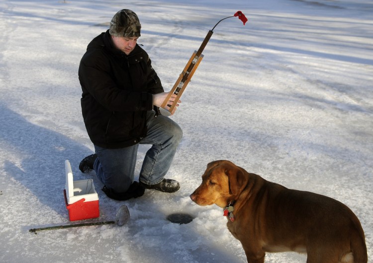 Chris Merrill, of Augusta, sets a trap Monday while ice fishing on Cochnewagon Lake in Monmouth. "There's plenty of ice in coves," he said of the late fall conditions.