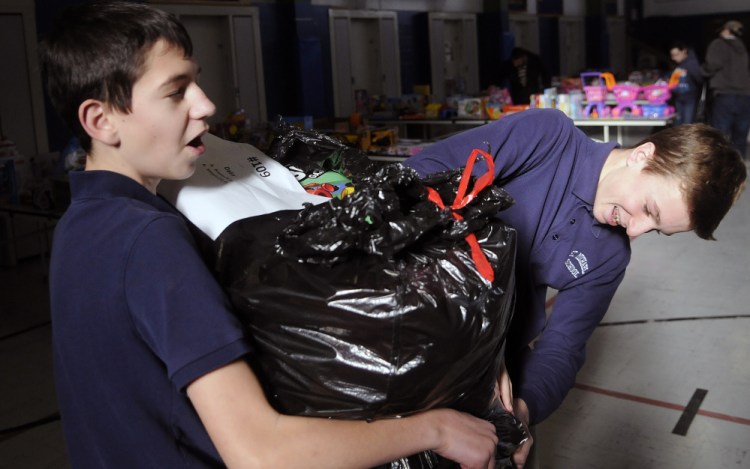 St. Michael School students Chris Bourdon, left, and Kyle Douin double-bag gifts distributed Tuesday by the Salvation Army at the private Catholic school in Augusta.