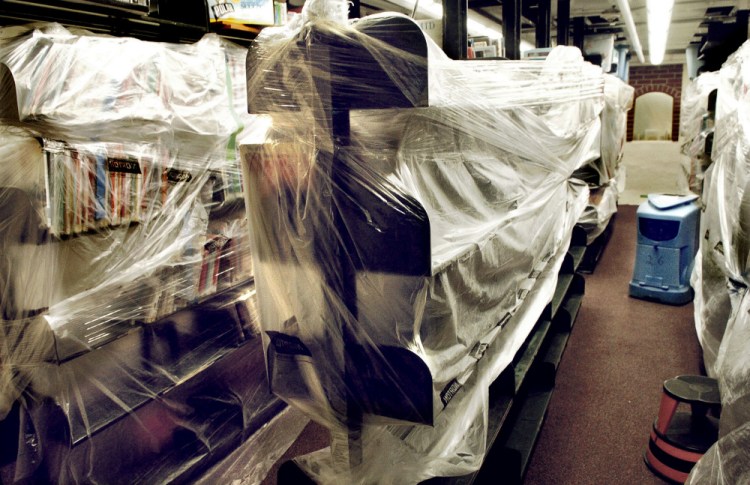 Stacks of books at the Waterville Public Library are covered with plastic Thursday as a dryer continues to dry out shelves and carpets after a burst water pipe caused serious damage last weekend.