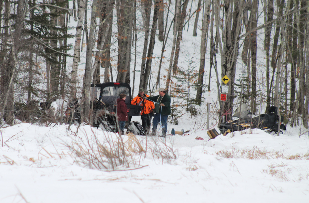 From left to right, Roberta Kemp, Max Kemp and Scott Kemp work to recover snowmobiles that got stuck in a bog in the Leeds/Wales area on Monday.