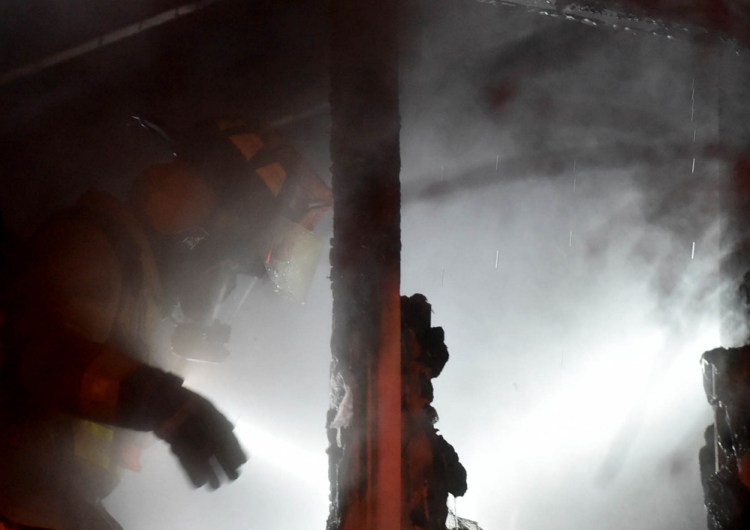 Firefighters look for remnants of a small house fire Saturday evening on John Avenue in Waterville.