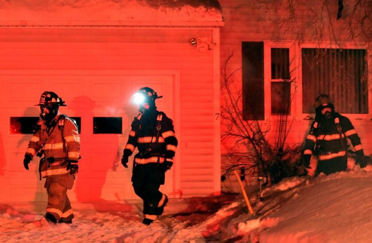 Firefighters look for remnants of a small house fire Saturday evening on John Avenue in Waterville.