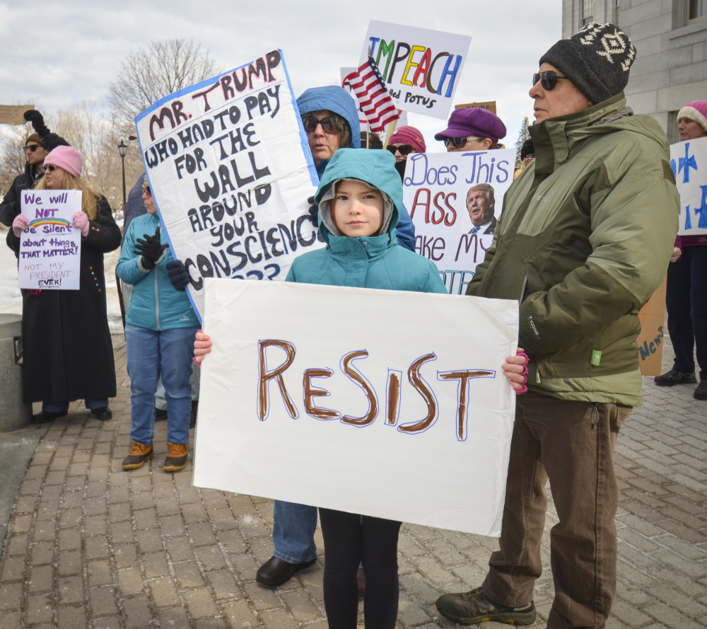 Ava Trout, front, of South China, joins her grandparents Monday at the Not My President's Day rally at the State House in Augusta. They were among several dozen demonstrators protesting President Donald Trump and his policies.