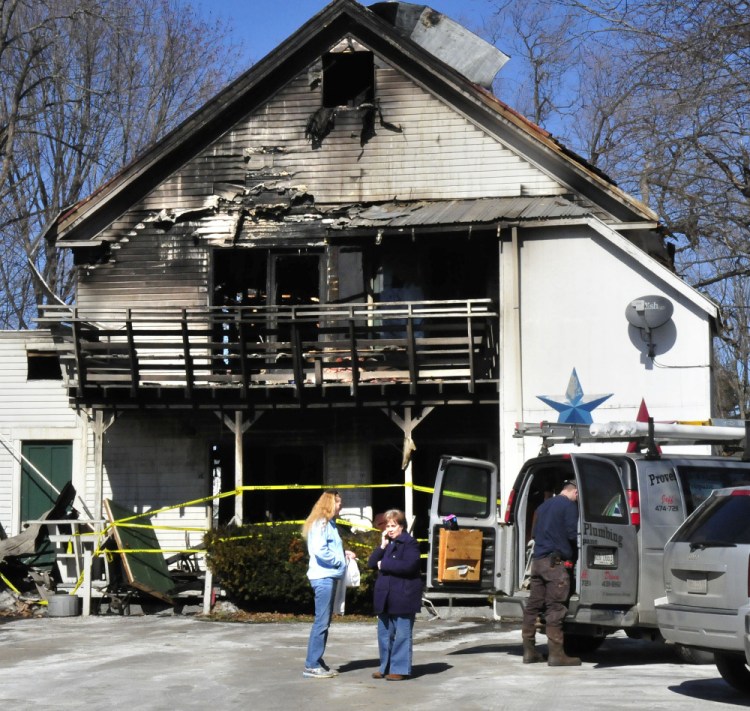 Madison apartment building owner Virginia Weems, right, speaks on a cellphone beside tenant Barbara Turner as a plumber makes repairs on Monday. Four of the building's seven apartments were destroyed by fire Saturday. The apartment Turner lives in with her husband did not burn but sustained smoke damage.