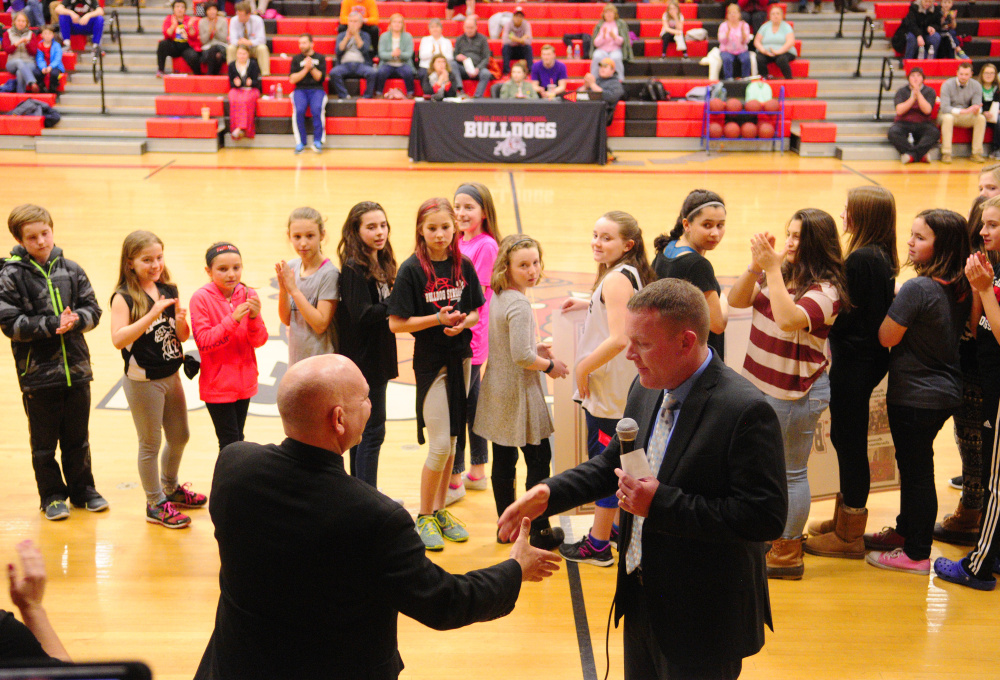 Hall-Dale Principal Mark Tinkham, left, shakes hands with Ryan Madore as Madore presents a $10,000 check during halftime of a unified basketball game against Carrabec on Wednesday. The money, raised by the Bulldog Strong Invitation basketball tourney, will go toward renovations of the school's Penny Gym.