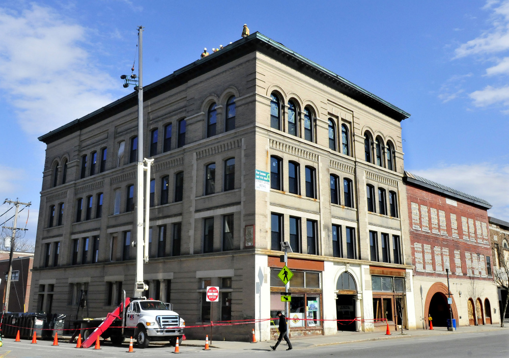 Workers can be seen on top of the former Hains building in downtown Waterville where a new roof is being installed on Monday.