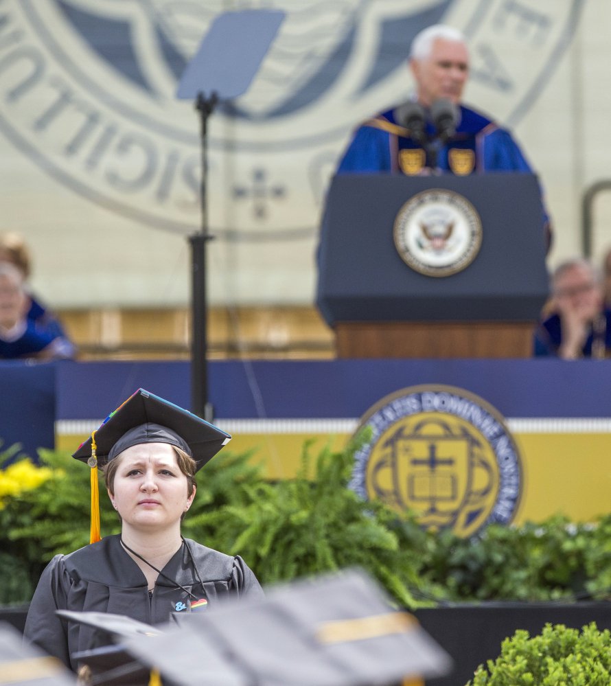 Notre Dame graduate Erin McNamee, a biology major in the school of science, stands with her back to Vice President Mike Pence in protest as he speaks in South Bend, Ind.